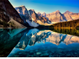 A lake with snow-capped mountains reflected in its still water.